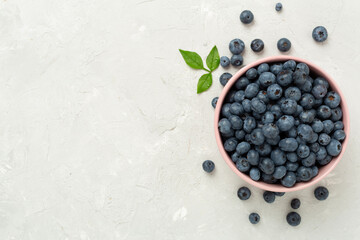 Bowl with fresh bright blueberries on concrete background,top view