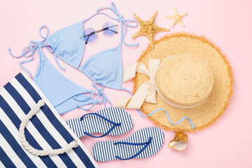 Blue bikini with beach accessories on color background, top view