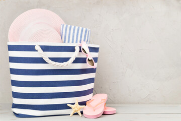 Blue beach bag with summer accessories on wooden table