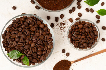 Roasted coffee beans with leaves on concrete background,top view