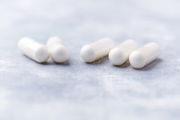 Creatine capsules on bright wooden background. Soft focus. Close up. Copy space.