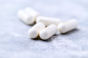 Creatine capsules on bright wooden background. Soft focus. Close up. Copy space.	