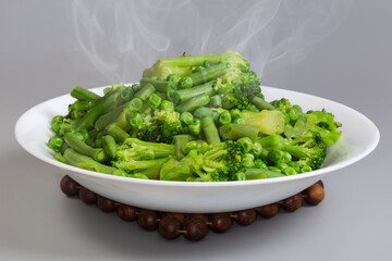 Freshly boiled green vegetables mixture on dish on gray background
