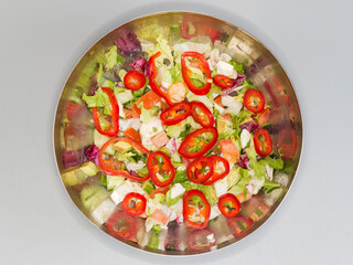 Vegetable salad with soft cheese in metal bowl, top view