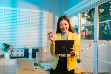 Dedicated businesswoman working late at night in a dimly lit office, focused on her laptop amidst...