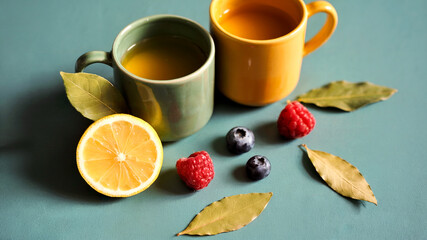 Fresh Lemon, Berries, and Herbal Tea in Colorful Cups on Blue Background