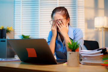 Exhausted businesswoman works late into the night, overwhelmed by stress, deadlines, and endless...