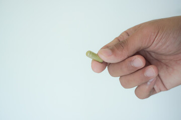 Male hand pouring green medicine capsules from plastic bottle into a palm, antibiotic pills, vitamins, painkillers, isolated on transparent background. healthcare and treatment concept