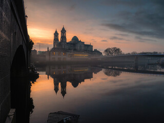 View on Church of Saints Peter and Paul at dusk. Warm color light. Cloudy sky reflects in river...