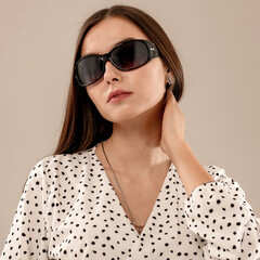 Portrait of pretty young woman with sunglasses. Stylish model posing in bright minimalist interior. The natural lighting and soft warm interior studio setting.