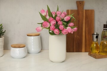 Bouquet of beautiful tulips in vase on white marble countertop indoors