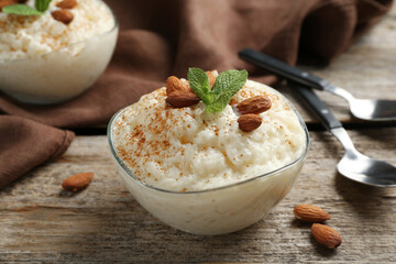 Delicious rice pudding with cinnamon, almonds and mint served on wooden table, closeup