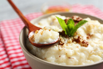 Delicious rice pudding with walnuts and mint on table, closeup
