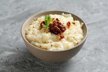 Delicious rice pudding with walnuts and mint on grey table, closeup