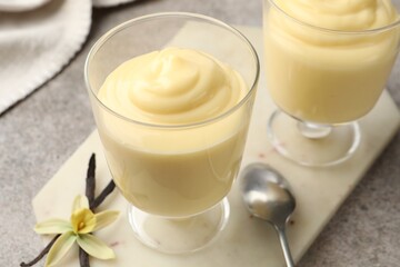 Tasty vanilla pudding, pods and flower on grey table, closeup