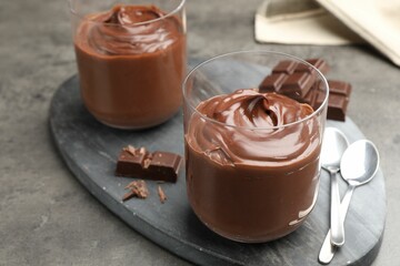 Tasty pudding and pieces of chocolate on grey table, closeup