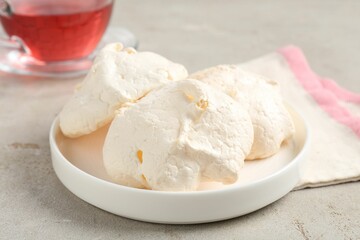 Delicious homemade meringue cookies and tea on gray table, closeup