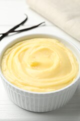 Tasty vanilla pudding and pods on white wooden table, closeup