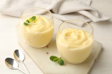Tasty vanilla pudding with mint served on white wooden table, closeup