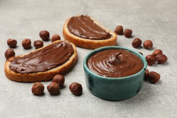 Toasts with tasty chocolate hazelnut spread and nuts on grey table, closeup