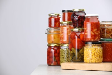 Many jars with different pickled products on light grey table, space for text