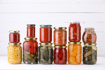Many jars with different pickled products on white table