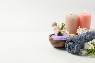 Spa composition with cosmetic products, beautiful flowers and burning candles on white table, closeup. Space for text