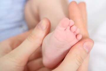 Mother with her little baby on bed indoors, closeup