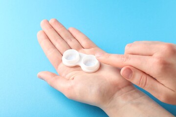 Woman with contact lenses on light blue background, closeup