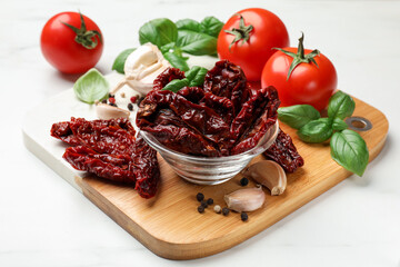 Delicious sun dried tomatoes, fresh vegetables and spices on white marble table, closeup