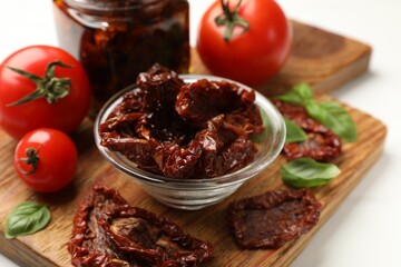 Tasty sun dried tomatoes and fresh vegetables on white table, closeup