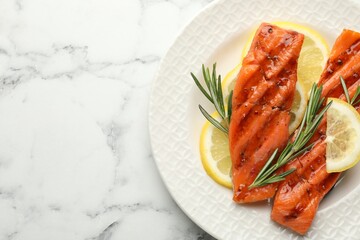 Seafood. Tasty grilled salmon served with rosemary and lemon on white marble table, top view. Space for text