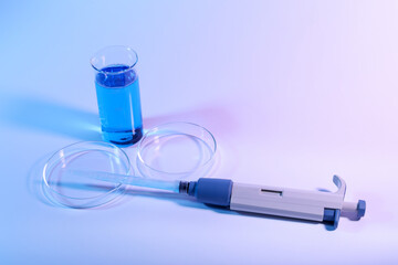Petri dishes, micropipette and beaker with sample on light background