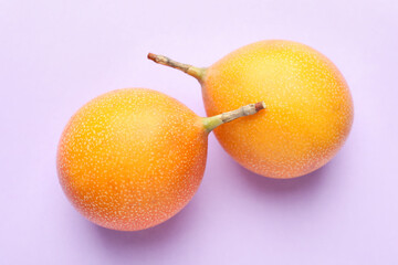 Ripe yellow passion fruits on lilac background, flat lay