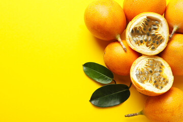 Ripe passion fruits and leaves on yellow background, flat lay. Space for text