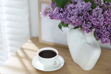 Bouquet of beautiful lilac flowers and coffee on wooden table