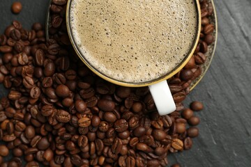 Aromatic coffee in cup and beans on black table, flat lay