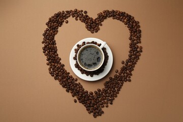 Aromatic coffee in cup and heart shaped of beans on beige background, flat lay