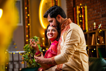 Obraz premium Indian couple in festive attire, man surprises wife with bracelet, sweets and gifts around