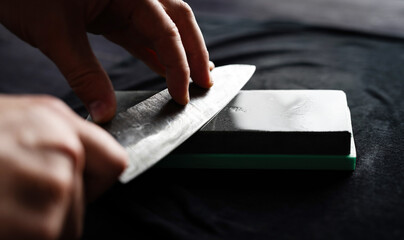 Male Hands Sharpening Kitchen Knife With Whetstone