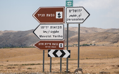 Signpost on route 449 in the desert near Jericho in Israel; signs present information in Hebrew, Arabic, and English