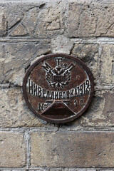 Close Up Of A Rusty Round Metal Survey Benchmark (Nivelirоvka) From 1912, Imperial Russia, Embedded In An Old Brick Wall. Historical Geodetic Mark.