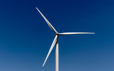 White, three-bladed wind turbine against a dark blue sky
