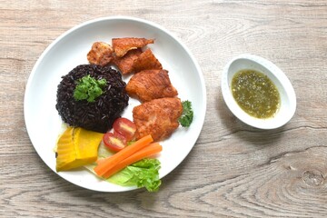 grilled slice pangasius dory fish on black riceberry with pumpkin carrot lettuce and tomato on plate dipping Thai spicy seafood sauce