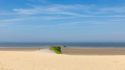 Stone pier on the abandoned beach of Blankenberge, Belgium, with a vanishing point in the sea and a blue sky