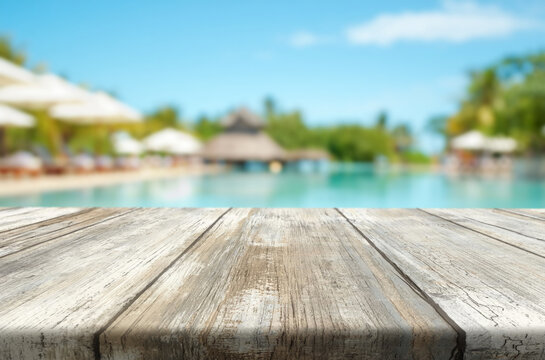 Relaxing view of a tropical poolside with wooden table under bright sky and lush palm trees