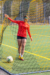 Sporty girl scores a goal into the goal. Football concept. Girl on the football field.