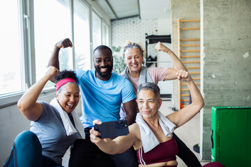 Diverse group of happy seniors and fitness trainer taking a post-workout selfie at the gym