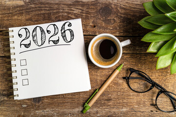 New year resolutions 2026 on desk. 2026 goals list with notebook, coffee cup, plant on wooden table. Resolutions, plan, goals, action, checklist, idea concept. New Year 2026 template, copy space