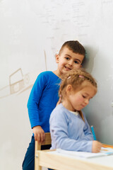 Brother and Sister Sitting in the Warmth of Their Room, Learning to Draw and Write Their First Letters.